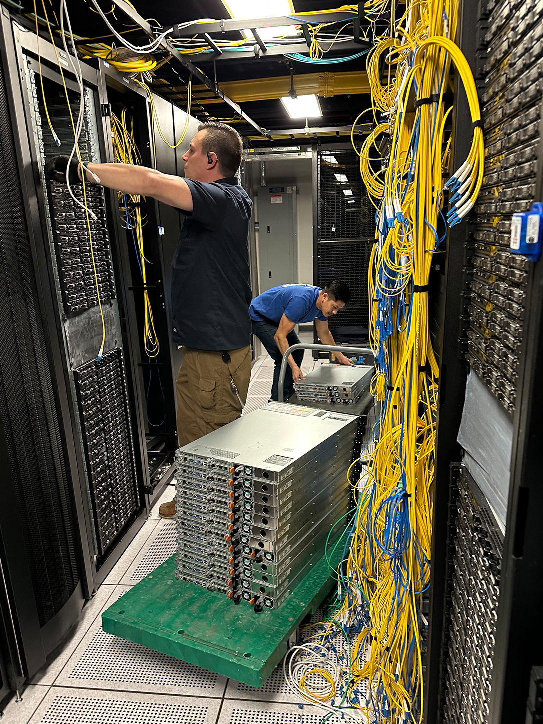 Technical migration team de-racking and stacking network blade servers on a platform truck for a data center lift-and-shift project.