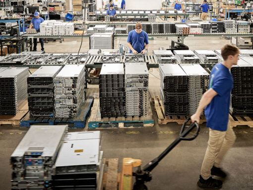 Warehouse operations showing an IT asset management specialist using a pallet jack to transport decommissioned enterprise servers.