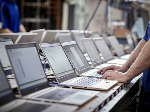 Close-up of hands typing on a laptop computer connected to an onsite data sanitization system for secure device refurbishment.