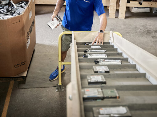 OceanTech technician sorting decommissioned enterprise hard drives onto a processing conveyor line for secure physical data destruction.
