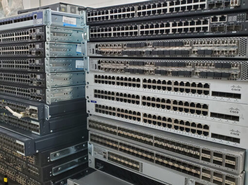 Organized stacks of decommissioned Cisco switches and network routing hardware sorted for hardware remarketing evaluation