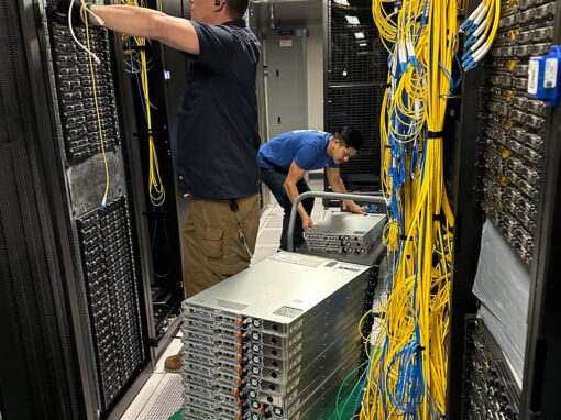 Technical migration team de-racking and stacking network blade servers on a platform truck for a data center lift-and-shift project.